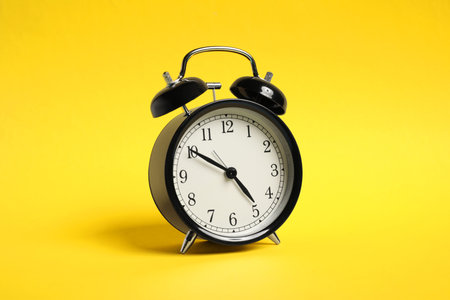 One black alarm clock on yellow backgroundの写真素材