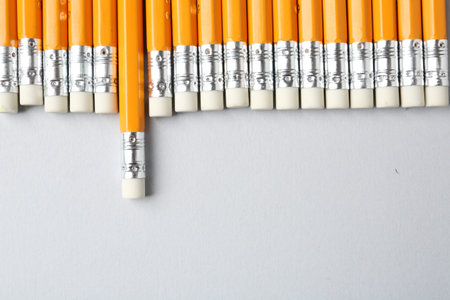 Pencils with erasers on grey background, flat lay. Space for text