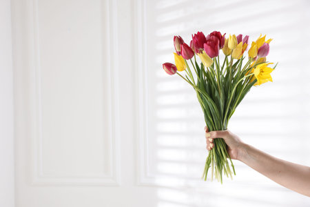 Woman with bouquet of beautiful tulips near white wall, closeup. Space for textの写真素材