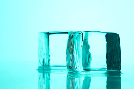 Cubes of clear ice on light blue background, closeup