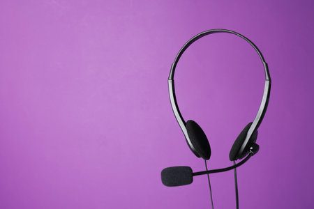 Headset with microphone in air on purple background, space for textの写真素材