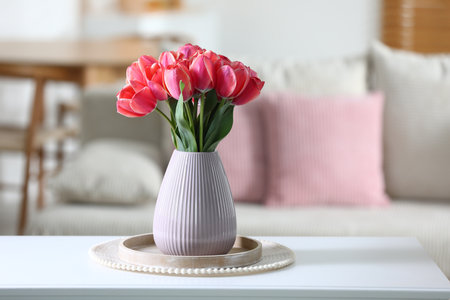 Beautiful tulips in vase on white table indoorsの写真素材