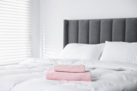 Clean terry towels on bed at homeの写真素材