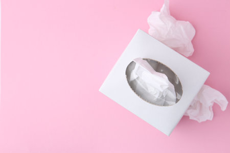 Box with paper handkerchiefs and crumpled tissues on pink background, flat lay. Space for textの写真素材