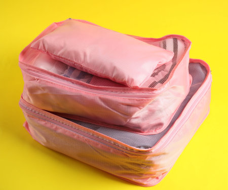 Packing cubes with clothes on yellow background, closeup