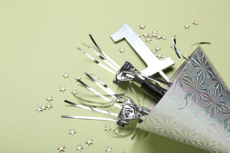 Party hat, blowers, topper and confetti on light green background, closeup