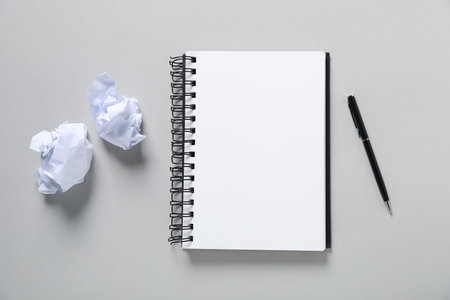 Open blank notebook, pen and crumpled paper on light grey background, flat layの写真素材