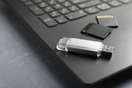 Usb flash drive, SD memory cards and laptop on grey textured table, closeupの写真素材