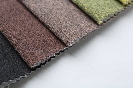 Samples of different fabrics on white background, closeup. Space for text