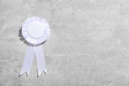 White award ribbon on light grey table, top view. Space for textの写真素材