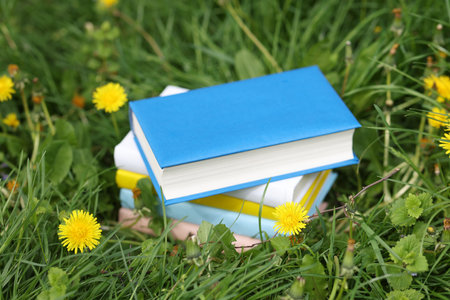Stacked books on green grass outdoors, closeupの写真素材