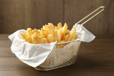 Tasty french fries on wooden table, closeup