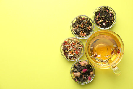 Delicious herbal tea in glass cup and dry leaves on green background, flat lay. Space for textの写真素材
