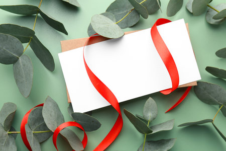 Blank card, ribbon and eucalyptus branches on light green background, flat layの写真素材