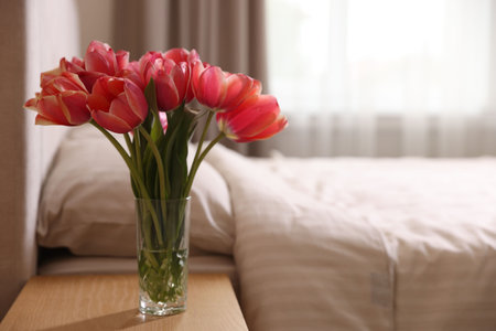 Bouquet of beautiful tulips on side table in bedroom. Space for textの写真素材