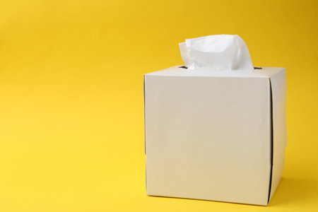 Box with paper handkerchiefs on yellow background. Space for textの写真素材