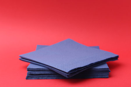 Stack of blue handkerchiefs on red background, closeup. Space for textの写真素材
