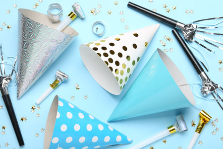 Flat lay composition with party hats and confetti on light blue background