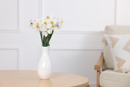 Beautiful daffodils in vase on wooden table at home. Space for textの写真素材