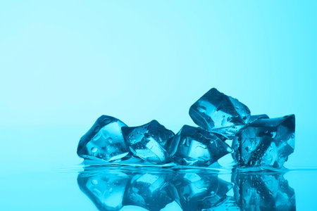 Cubes of clear ice on light blue background, closeup. Space for text