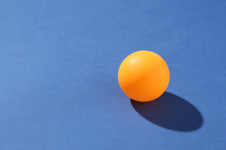 One ping pong ball on blue background, closeup. Space for textの写真素材