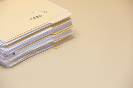 File folders with documents and paper clips on pale yellow background, closeup. Space for textの写真素材