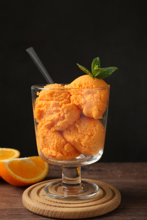 Balls of tasty orange sorbet in dessert bowl, fresh fruit and mint on wooden table, closeupの写真素材
