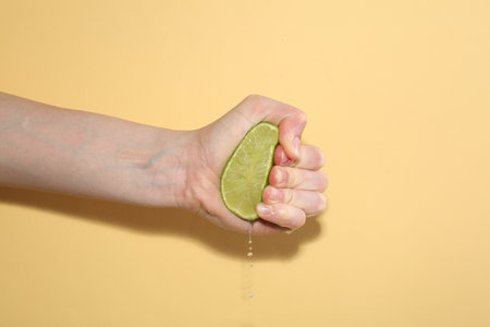 Woman squeezing lime on yellow background, closeupの写真素材