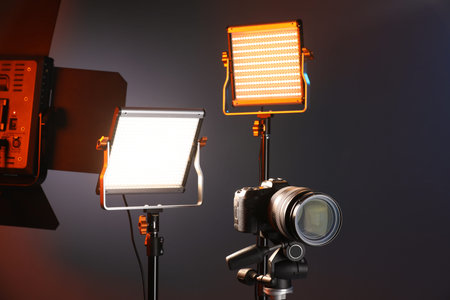 Professional lighting equipment and camera on color background