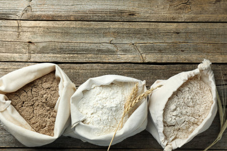 Different types of flour in bags on wooden table, flat lay. Space for textの写真素材