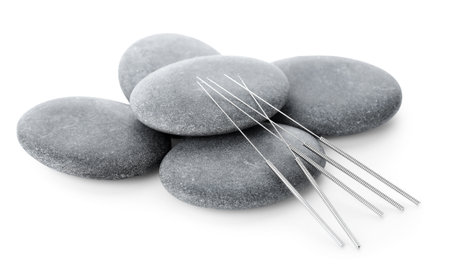 Acupuncture needles and spa stones isolated on whiteの写真素材