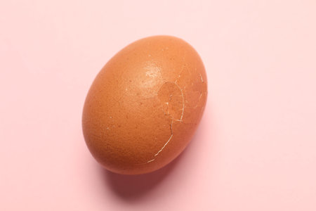 One egg with cracked shell on pink background, closeupの写真素材