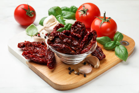 Sun dried tomatoes, fresh vegetables and spices on white marble table, closeupの写真素材