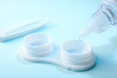 Dripping solution into case with contact lenses on light blue background, closeupの写真素材