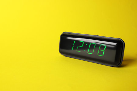 Digital alarm clock showing 12:08 o'clock on yellow background, space for textの写真素材