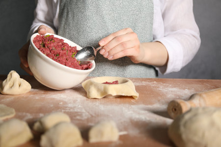 Woman making khinkali on table in kitchen, closeupの写真素材