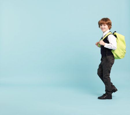 Cute schoolboy with backpack on light blue background, space for textの写真素材