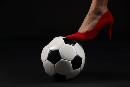 Woman in high heeled shoe with soccer ball on dark background, closeupの写真素材