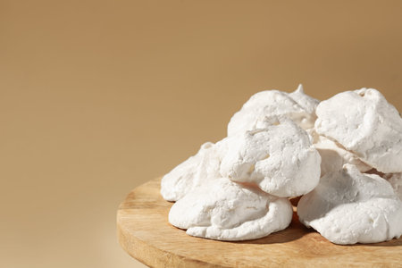 Delicious homemade meringue cookies on wooden table against beige background, closeup. Space for textの写真素材