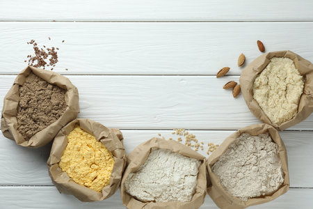 Different types of flour in paper bags on white wooden table, flat lay. Space for textの写真素材