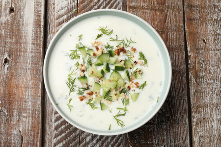 Tasty cucumber soup with dill and nuts in bowl on wooden table, top viewの写真素材