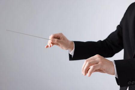 Professional conductor with baton on light grey background, closeup. Space for textの写真素材