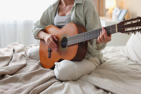 Young woman playing guitar at home, closeupの写真素材