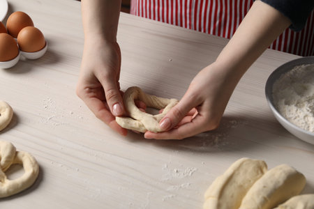 Woman making pretzel at white wooden table, closeupの写真素材