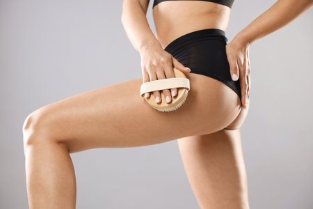 Woman doing anti cellulite massage with brush on grey background, closeupの写真素材