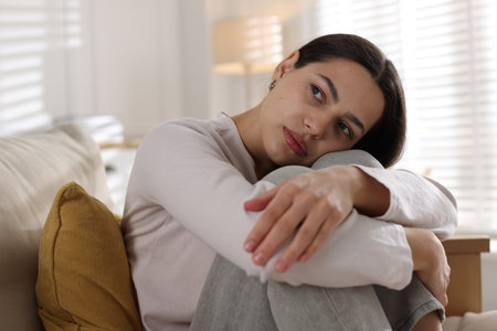 Depressed young woman on sofa at homeの写真素材