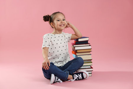 Cute girl with books on pink backgroundの写真素材