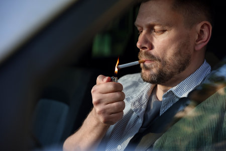 Man lighting cigarette in car, view from outsideの写真素材