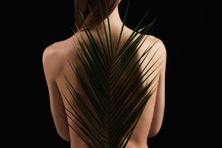 Woman with palm leaf on black background, closeupの写真素材