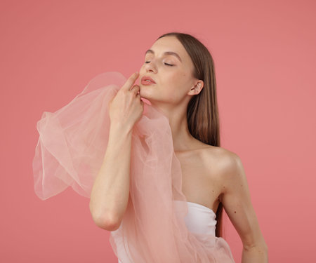 Young woman with beautiful fabric on pink backgroundの写真素材